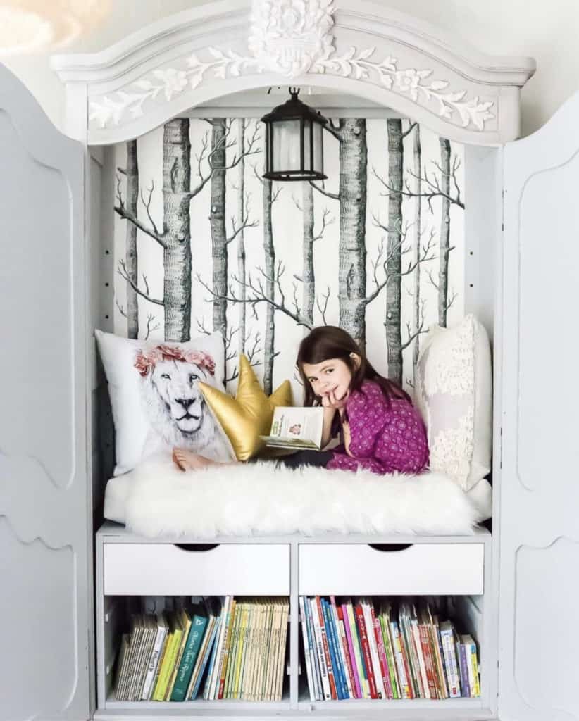 Young girl reading in a cosy DIY up-cycled armoire Narnia themed reading nook armoire