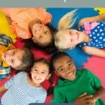 pinterest graphic with 5 smiling multiracial children lying on the floor in a circle with their heads together. Text reads " What is emotional literacy? An introduction"