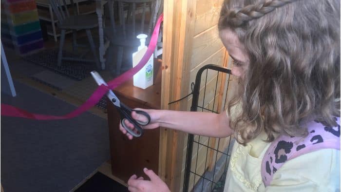 primary school girl cutting a red ribbon to mark the opening of Positive Primary Kids' tutoring cabin