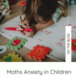 a little girl lies face down on the floor on top of a giant piece of paper full of times tables